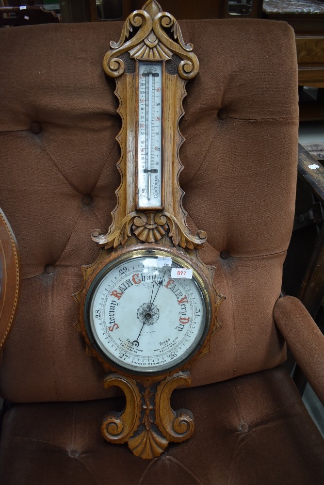 A late 19th or early 20th Century oak framed banjo thermometer in ornately carved case