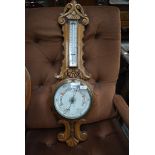 A late 19th or early 20th Century oak framed banjo thermometer in ornately carved case