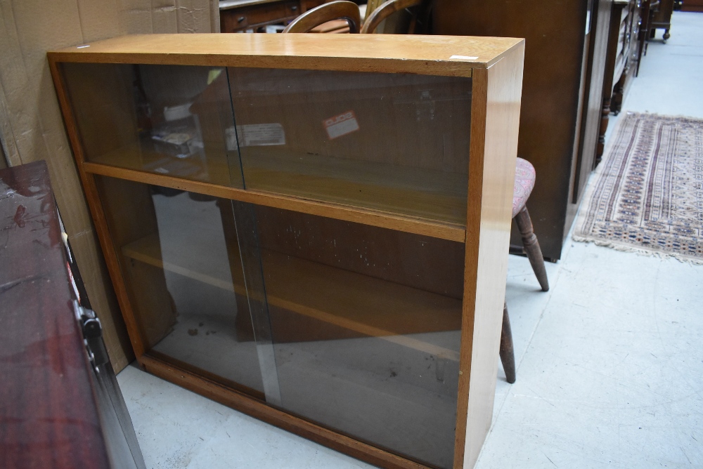 A mid 20th Century golden oak low bookcase, having double glass sliding doors, width approx. 92cm