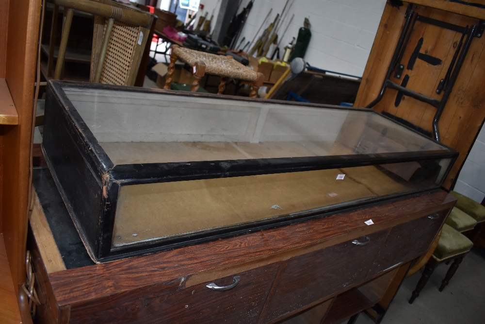 An Edwardian long glazed display cabinet having ebonised frame