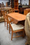 A modern mid century designed dining set by Ercol four ladder back chairs and matching circular