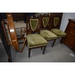 A set of three late Victorian carved frame dining chairs with green satin upholstery