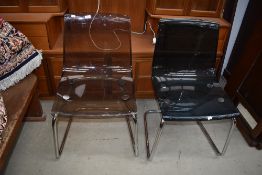 Two near matching chrome and perspex dining chairs, of early 1970's design, and a pair of designer