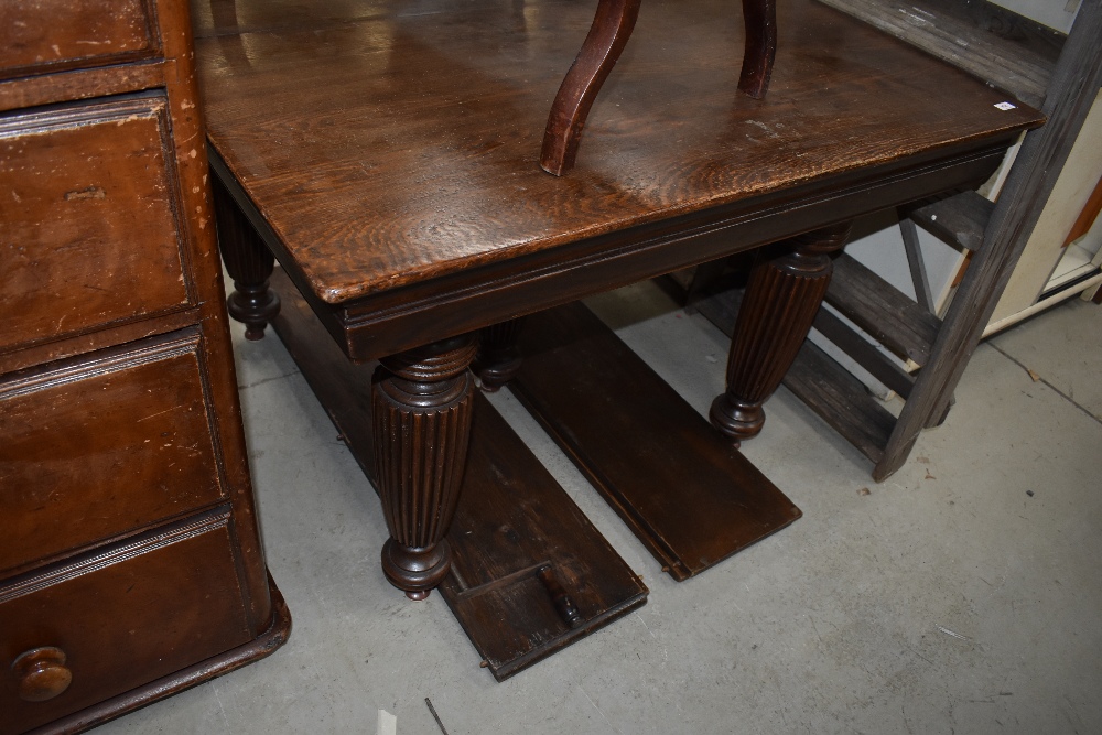 A late Victorian oak windout dining table having fluted legs, winder and four additional leaves