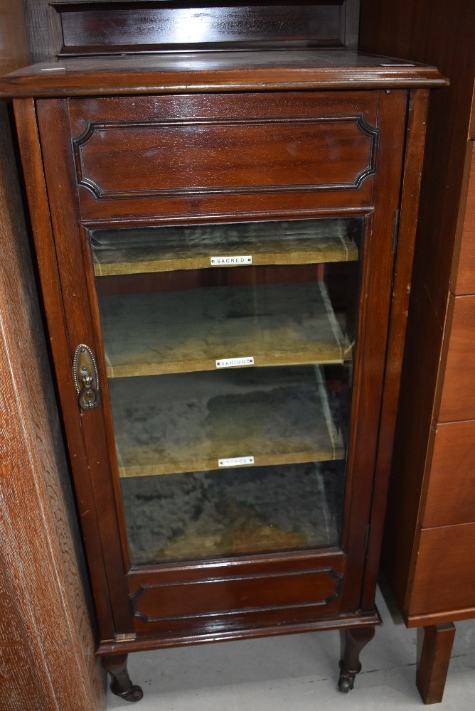 An Edwardian mahogany music cabinet , glass front with lined and labelled shelves, ledge back