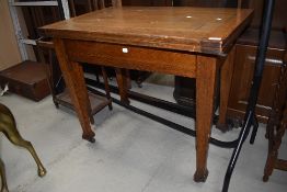 Am early 20th Century oak fold out dining table on tapered legs and brass casters, closed size