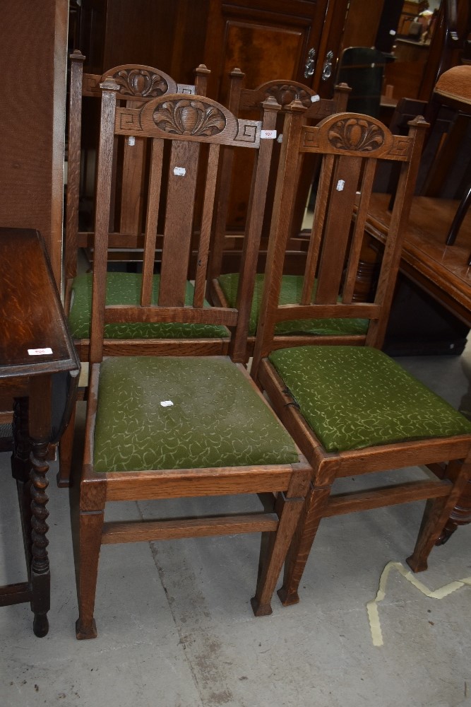 A set of four early 20th Century golden oak highback dining chairs having drop in seats