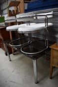 A vintage chrome framed and black glass dining table with four chrome and white vinyl modernist