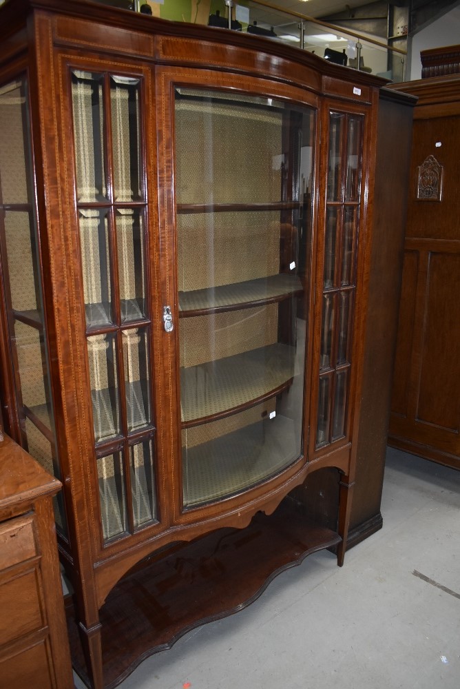 An Edwardian mahogany and inlaid display cabinet having lined interior, central bow front, on square