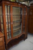 An Edwardian mahogany and inlaid display cabinet having lined interior, central bow front, on square