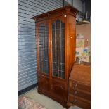 An art nouveau book case having leaded and rolled glass frontage with under cupboard