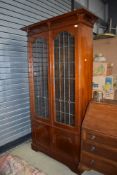 An art nouveau book case having leaded and rolled glass frontage with under cupboard