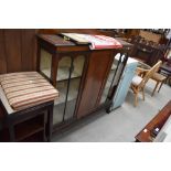 An early 20th Century mahogany display cabinet having ledge back, central cupboard flanked by