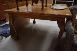 An early 20th Century oak dining table, having plank style top, on heavy cabriole legs and raised