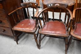 A pair of early 20th Century oak captains chairs with later leather studded seats