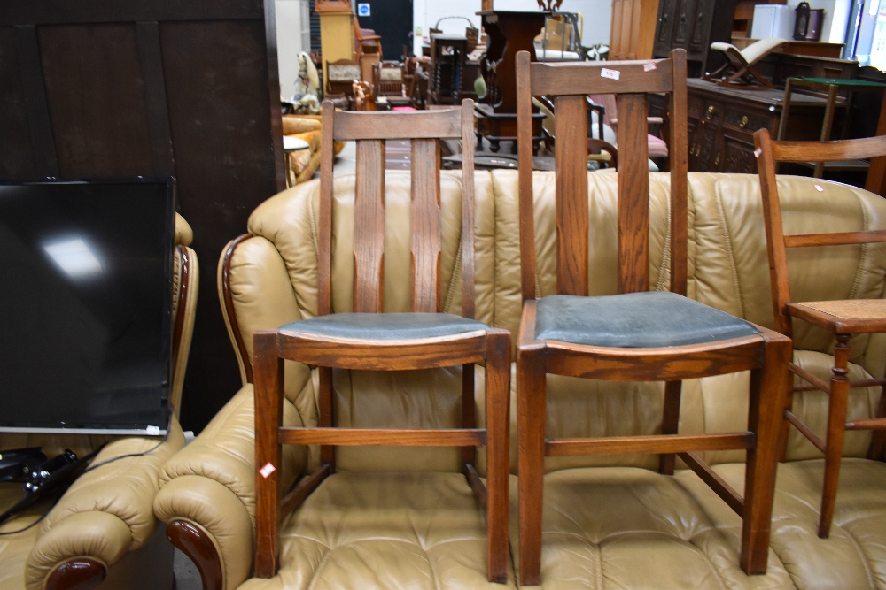 A pair of early 20th Century oak railback dining chairs with green vinyl drop in seats