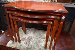 A modern nest of three mahogany effect tables