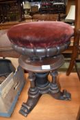 A late 18th century revolving piano stool on tripod base with carved column base