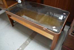 A low mid century design teak coffee table having smoked glass top