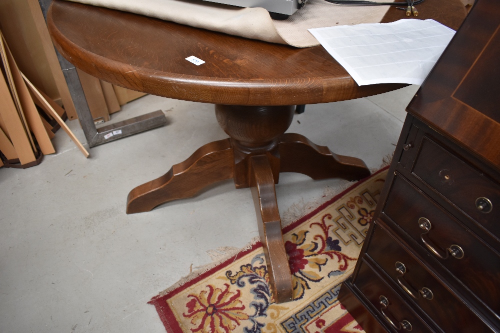 A modern oak circular dining table having bulbous column and chunky legs