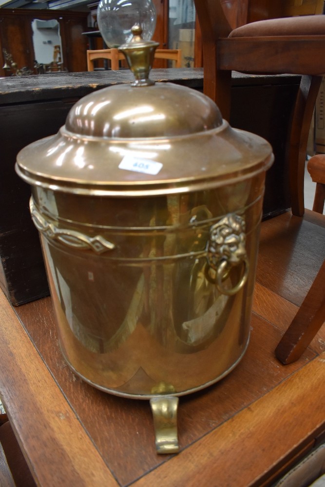 A coal basket in brass having lion head handles and three foot base