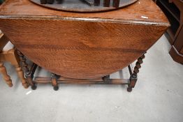 An early to mid 20th Century oak twist gate leg dining table, leaf damaged but present