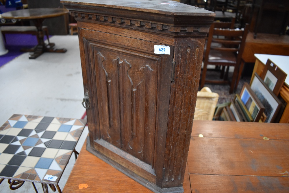 A small oak corner cupboard having a religious style