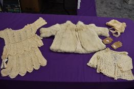 A collection of baby and childrens clothing including fur coat and bonnets, mostly around 1920s.