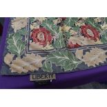 A Liberty of London silk scarf having floral pattern in red and green on grey ground.