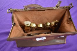 A vintage brown leather clasp top overnight/vanity bag having a set of ladies accessories to