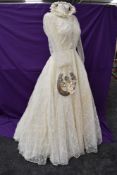 A full skirted 1954 wedding dress having net overlay, long sleeves and button detail to front of