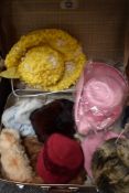 A suitcase containing an assortment of vintage hats and a fur stole, various eras and styles.