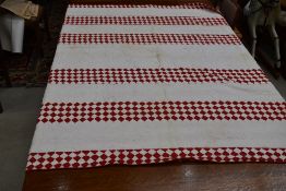 A large red and white patchwork quilt, having different patterns to front and reverse, some age