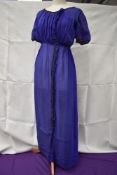 An early 20th century blue silk or silk blend dress having metallic thread edging and glass bead