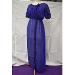 An early 20th century blue silk or silk blend dress having metallic thread edging and glass bead