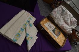 A suitcase containing a vintage candlewick bed throw, an ochre nylon double bed throw in packaging