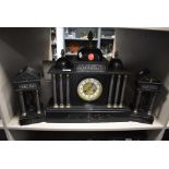 A slate mantel clock with matching garnitures