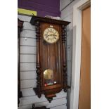 A British enamelled faced wall clock having weighted pendulum in mahogany case