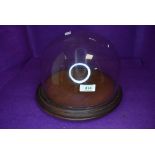 A cheese board or similar cake stand having glass dome top with oak plinth