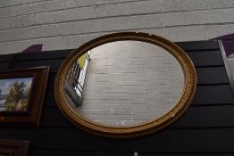 An oval framed gilt and gesso mantle mirror