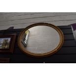 An oval framed gilt and gesso mantle mirror