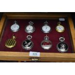 A glazed display case containing eight pocket watches or time pieces
