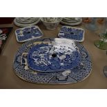 Four antique blue and white ware willow pattern charger and meat drainers large oval having stains