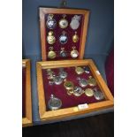 Two glazed display cases containing twenty one pocket watches or time pieces
