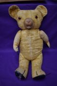 A mid 20th century straw filled teddy bear having plastic eyes, rubber nose and mouth, padded paws