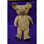 A mid 20th century straw filled teddy bear having plastic eyes, rubber nose and mouth, padded paws