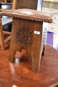 An arts and crafts stool having carved sides with decorative leather worked top
