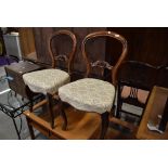 A pair of balloon back rose wood dining chairs with carved detailing