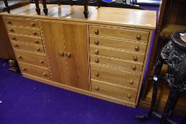 A golden oak entertainment cabinet, having divided cupboard section flanked by segmented drawers,