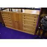 A golden oak entertainment cabinet, having divided cupboard section flanked by segmented drawers,